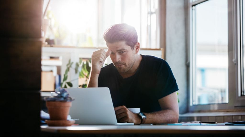 A man sits at his laptop attempting to write a LinkedIn about section