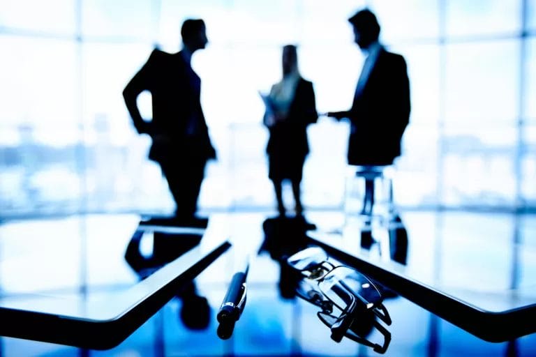 Executives in the background with pen on desk in focus